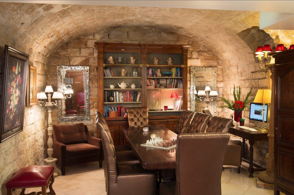 Salon bibliothèque sous les voûtes de pierre au sous-sol de l'Hôtel des Marronniers à PAris 6 - Hôtel Saint-Valentin Paris