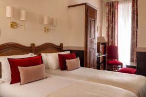 hotel chambre familiale avec deux lits individuels, coussins roses, placard en bois