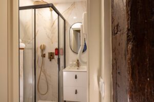 salle de bain chambre lit king size avec douche, miroir rond et tiroirs