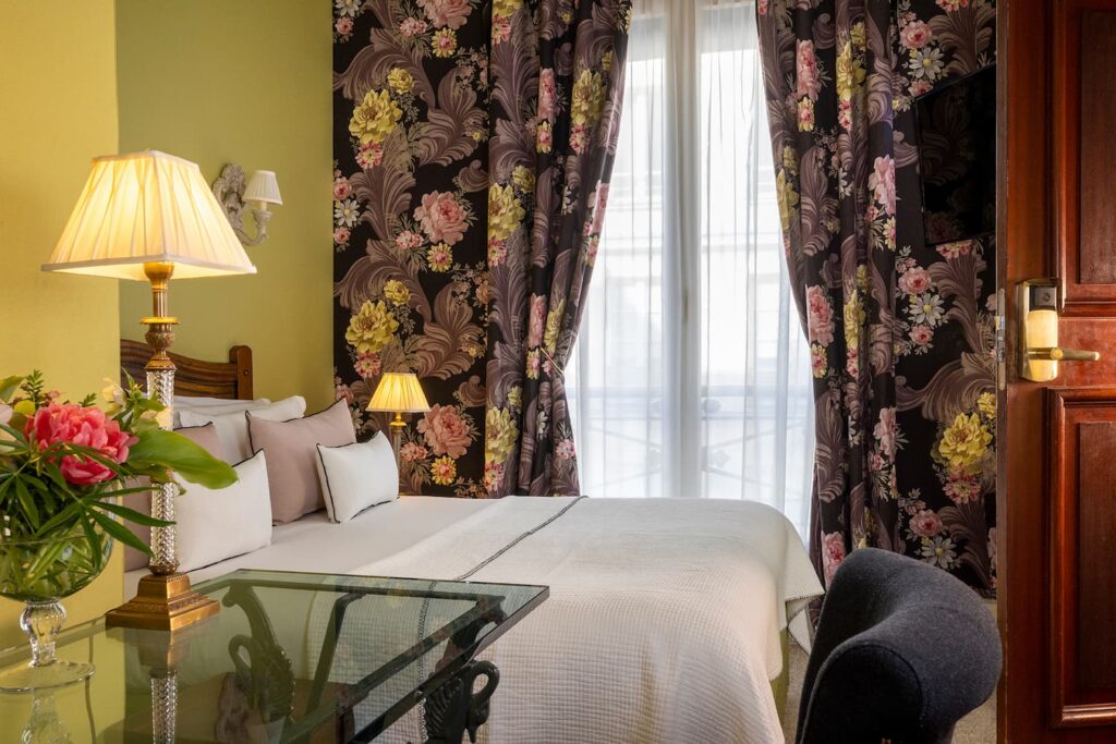 chambre double hotel de charme - lit avec coussins blancs et roses, rideaux et tissus vert