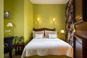 room with double white bed, green fabric and flower curtains - hotel with restaurant nearby Paris
