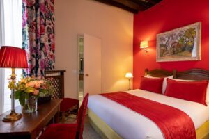 double room with bed, red fabric, flower curtain, painting and desk - double room boutique hotel
