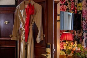 trench and umbrella on the door of a room with flower fabric and tv - double room boutique hotel