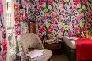 photo chambre hôtel de charme - fauteuil gris, tissus fleuri et livres