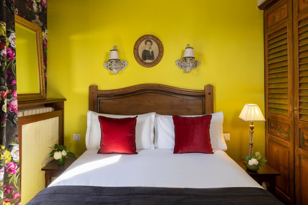 chambre hotel romantique : lit double avec coussins roses et tissus vert