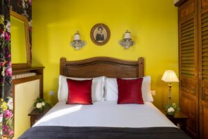 hotel in Paris - matrimonial white bed, yellow fabric, shower curtains, mirrors and pink pillows - romantic room Paris