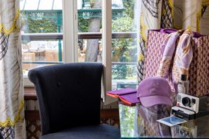 photo chambre hôtel de charme bureau avec casquette chaise noire et fenêtre ouverte sur jardin