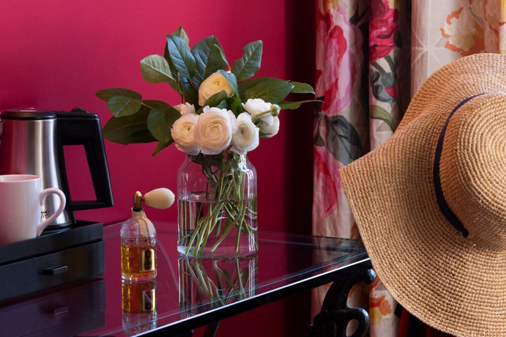 hotel in Paris - desk with courtesy tray, flowers and a hat - king size room Paris - hotel des marronniers