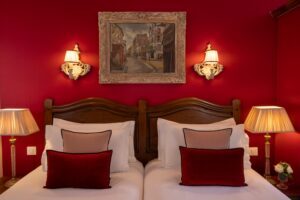 photo chambre hôtel de charme oreillers blancs, roses et parmes avec tableau au dessus du lit
