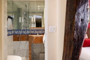 photo chambre hôtel de charme avec salle d'eau en marbre et lavabo porte ouverte