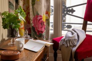 chambre individuelle hotel de charme avec bureau en bois, livre et écharpe devant fenêtre ouverte