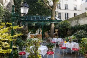 photo chambre hôtel de charme - jardin avec tables dressées pour le petit-déjeuner et pergola