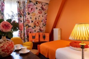 third bed, single bed - orange and flower fabric - yellow armchair, desk and flowers - large room in Paris - hotel in Paris