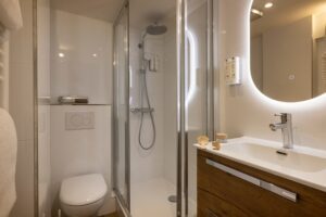 withe bathroom with shower, toilets, sink and amenities - large room in paris