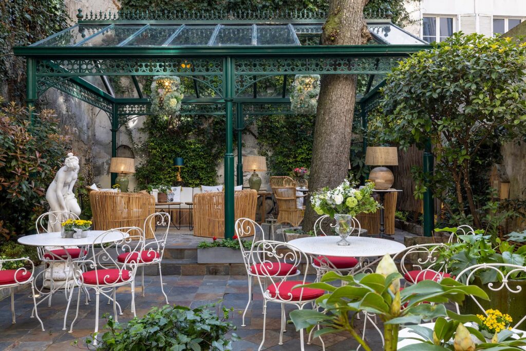 salon de thé hotel Paris 6 dans jardin hotel des marronniers - chaises, coussins rouges, tables et pergola