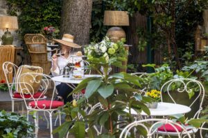 photo chambre hôtel de charme - cliente dans le jardin pour le salon de thé avec chapeau et livre