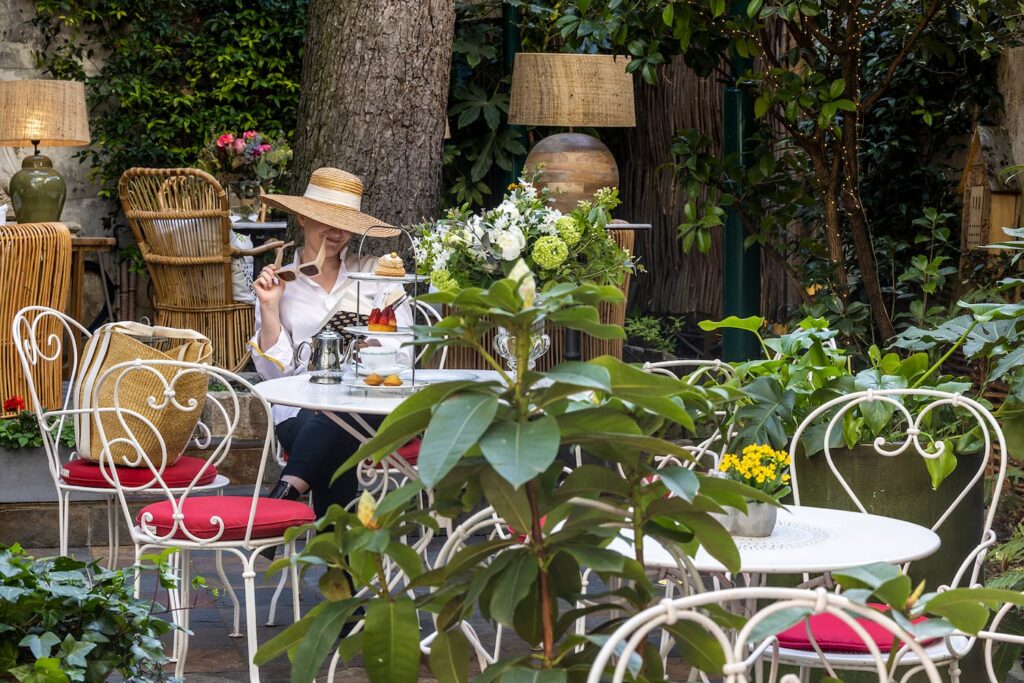 woman having a afternoon tea in Paris - garden of the hotel des marronniers