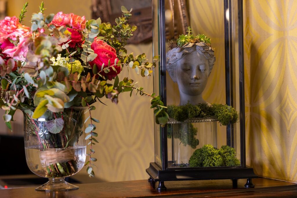 détails de la décoration de la réception de l'hôtel des marronniers proche notre-dame : fleurs, tête sculptée et tissu vert