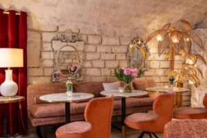 salon avec mobilier rose, tables en marbre et poutres apparentes - hotel restaurant proximité paris