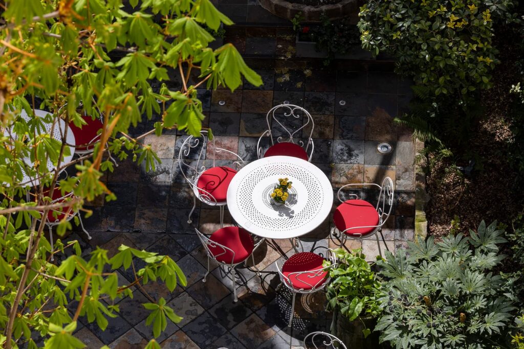 hotel near notre dame cathedral - garden of the hotel des marronniers with white table, and chairs