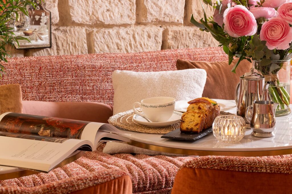 salon de thé de l'Hôtel des Marronniers, hôtel paris notre-dame, banquette et fauteuils roses, pierres apparentes, thé et cake