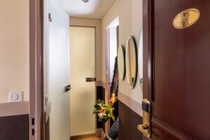 paris hotel with family rooms | corridor between the tow rooms and bathroom, with a man, flowers in his hand