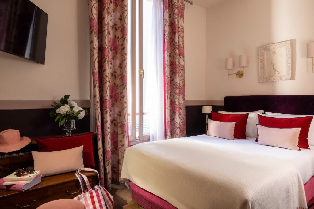 chambre quad pour 4 personnes hotel de charme paris : lit double, coussins roses, rideaux fleuris roses, grande fenêtre