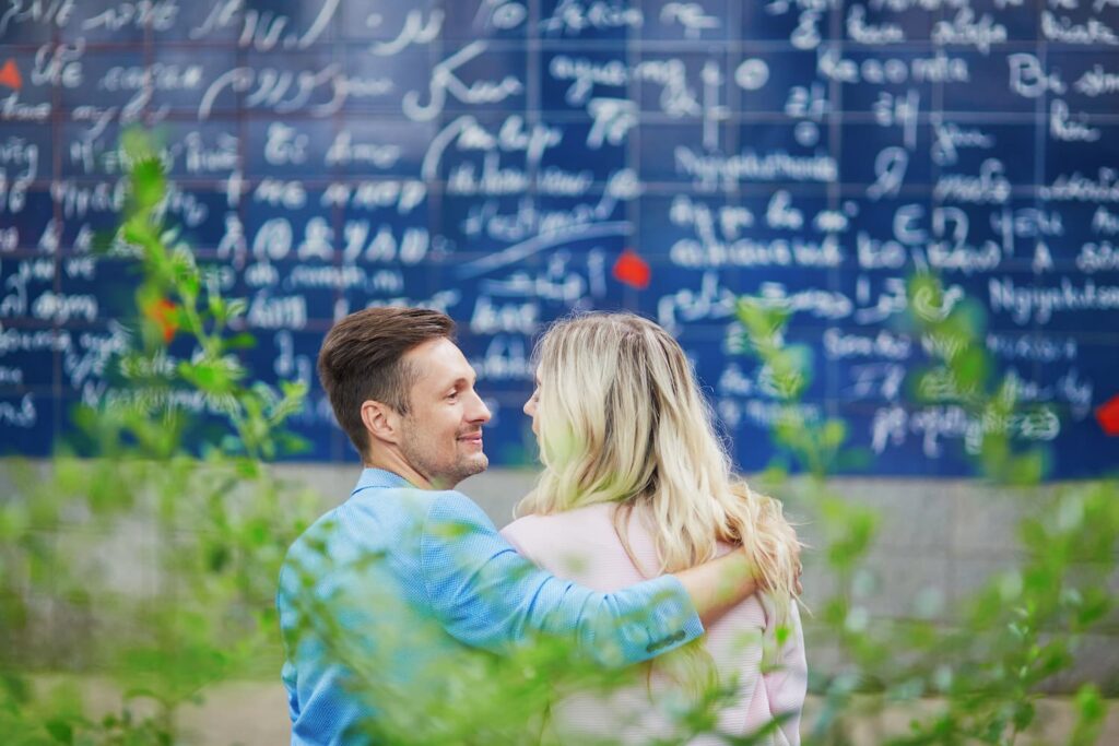 Un couple amoureux devant le mur des Je t'aime à Montmartre situé au Square Jehan Rictus